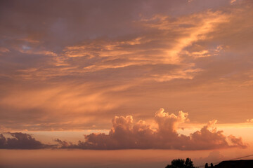 Bright colorful sunset sky with vivid smooth clouds illuminated with setting sun light spreading to horizon