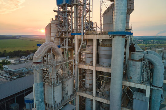 Cement plant with high factory structure and tower cranes at industrial production area. Manufacture and global industry concept