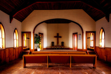 The interior of a small unused well kept but dusty country church with arched windows
