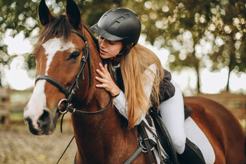 A young woman jockey lies on her horse and hugs her.