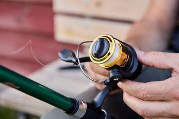 Fisherman is puts line on spinning fishing reel.