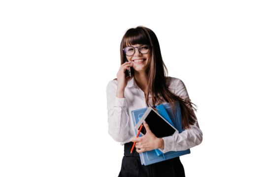 Cheerfull young brunette secretary in white shirt and black pants smiling holding diary tablet pencil talking by phone against transparent background.Pretty student girl happy after exam, smiling.