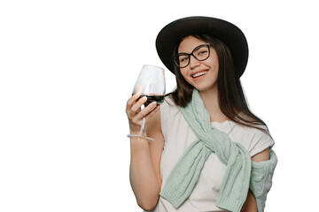 Happy brunette wearing white t-shirt hat and sweater tied up over her shoulders, holds a glass of...