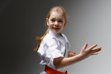 Hand strike in karate, defensive technique. Portrait of a smiling little girl at a sports training.