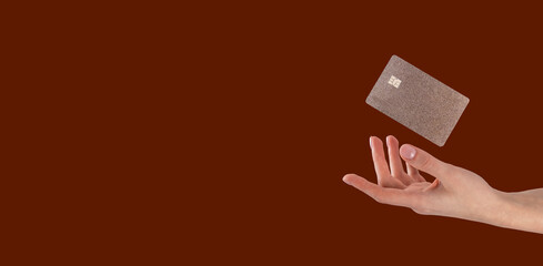 Hand with levitating flying bank credit debit card of gold color on ad banner with copy space for text