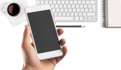 Hand holding a modern smartphone on office desk background.