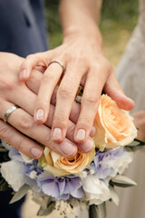 Obraz na płótnie Canvas Brautpaar legt Hände übereinander auf dem Brautstrauss um Eheringe zu präsentieren