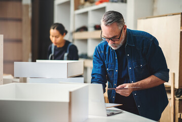 Fototapeta premium Senior caucasian man specialist worker measuring white shelf furniture in wood workshop, Small business in wood furniture industry.