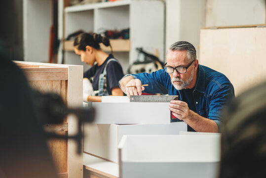 Senior caucasian man specialist worker measuring white shelf furniture in wood workshop, Small business in wood furniture industry.