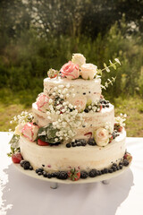 Hochzeitstorte mit frischen Beeren und Rosen in weiss 