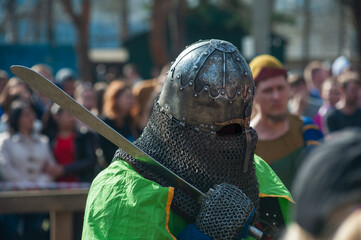 Medieval restorers fight with swords in armor at a knightly tournament, historical restoration of...