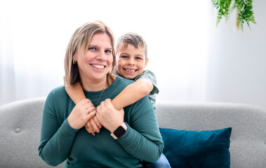 bonding sincere small kid boy with mother on cozy sofa together at home