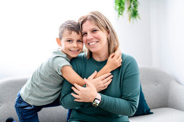 bonding sincere small kid boy with mother on cozy sofa together at home