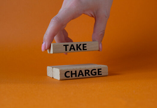 Take charge symbol. Wooden blocks with words Take charge. Businessman hand. Beautiful orange background. Business and Take charge concept. Copy space.