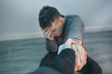 Unrecognizable man with problems receiving help from woman holding her hand. Helping hand concept