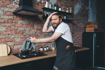 Frightened plump male cooking in kitchen