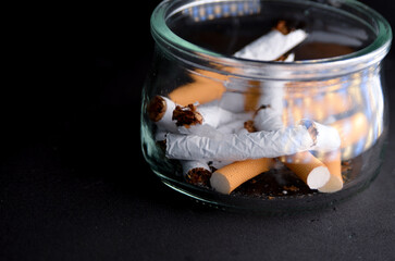 Group of broken cigarettes inside a glass ashtray. End of tobacco.
Concept of quitting smoking and leading a healthy life