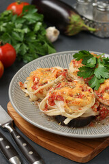 Spaghetti with eggplants, tomatoes and cheese on a gray plate on wooden board. Vegetarian food