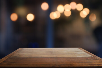 Empty wooden table in front of abstract blurred Cafe, restaurant at night. For montage product...