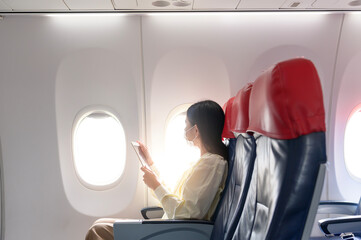 A young woman wearing face mask is traveling on airplane , New normal travel after covid-19...