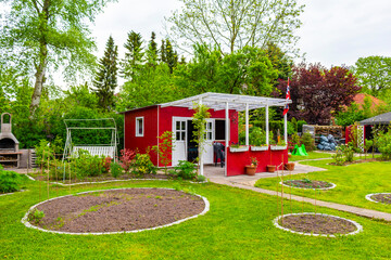 Green garden with red garden house in norwegian style Germany.