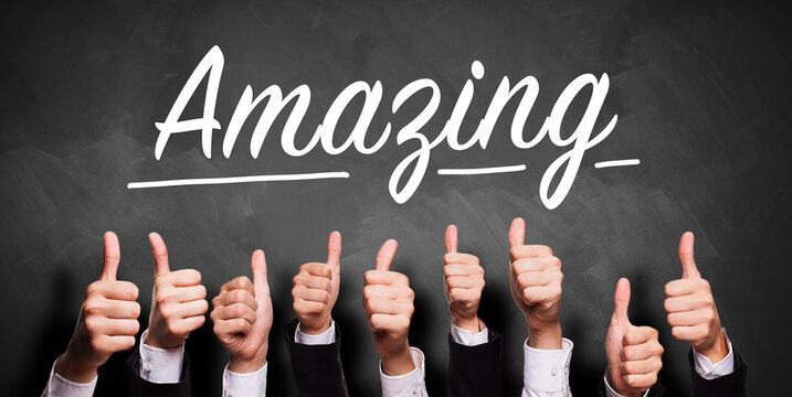many business hands with thumbs up gesture in front of a blackboard with the word AMAZING