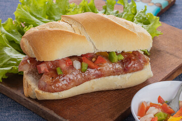 Choripan, typical argentine sandwich with chorizo and creole sauce on a wooden board. - obrazy, fototapety, plakaty