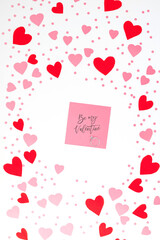 Engagement ring on the bottom of heart-shaped candy and valentine greeting card among red and pink paper hearts on white background. Valentine's Day, wedding and holiday concept. 