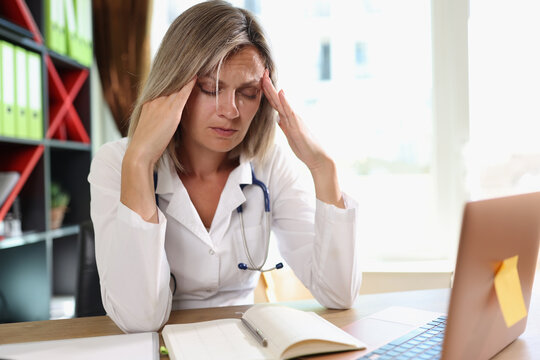 Exhausted female doctor having headache while working at clinic.
