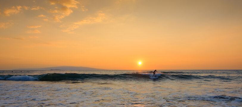 Silhouette of a surfer surfing at sunset, Maui, Hawaii, USA