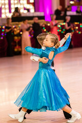 Fototapeta na wymiar Attractive young couple of children dancing ballroom dance. Girl and boy dancer international dancing.