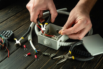 Professional electrical connection in the workshop of a master electrician. Close-up of the hands of an electrician during work. Cutting a cable or wire in a gray junction box