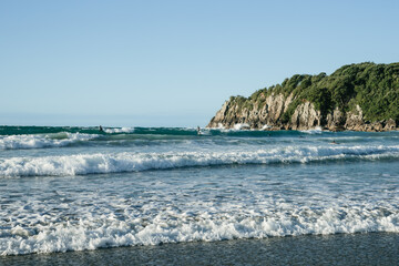 Surf waves roll in onto Main Beach, Mount Maunganui by Moturiki Island  on summer day.