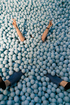 Overhead view of a woman playing in a ball pool filled with plastic blue balls