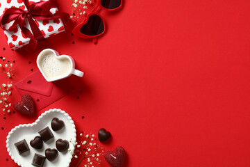 Happy Valentines Day composition. Flat lay gift box, heart shaped coffee cup, candy, candles, flowers on red background. Love, romance concept.