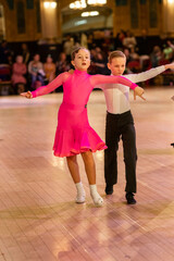 Fototapeta na wymiar Attractive young couple of children dancing ballroom dance. Girl and boy dancer international dancing.