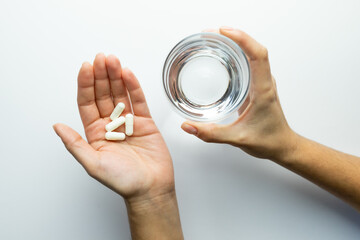 Hands holding pills and a glass of water, supplementation and health, vitamin replenishment concept - obrazy, fototapety, plakaty