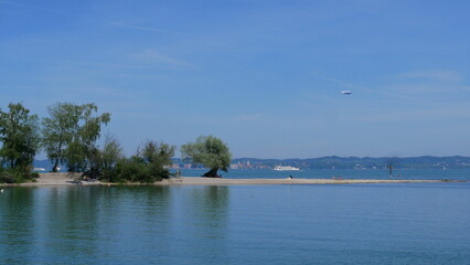 Blick auf den Sandstrand am Mehrerauer Seeufer bei Bregenz mit einer uraltem Silberweide und Blick nach Lindau und Bodenseeschiff sowie Zeppelin © turtles2