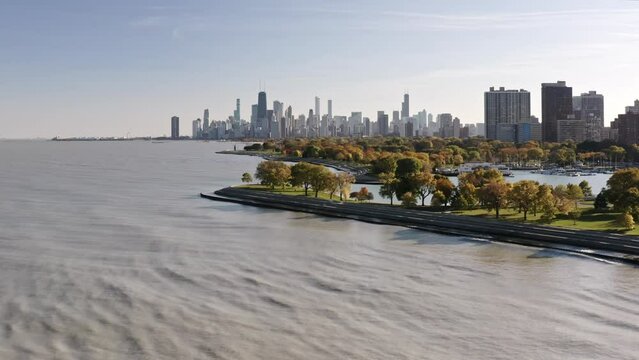 Panning in aerial drone view of the Chicago skyline from Lake Michigan near Belmont harbor on a sunny blue sky fall day.