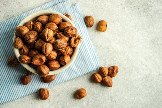 Overhead view of a Bowl of hazelnuts on a folded striped napkin