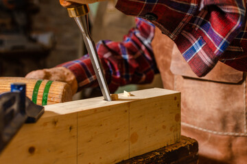 Close-up of a chisel drilling a block of wood in a carpentry workshop