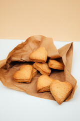 Shortbread cookies in the form of hearts in a brown paper bag on a white table. Front view