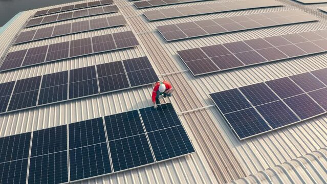 Male engineer maintaining solar cell panels on building rooftop. Technician working outdoor on ecological solar farm construction. Production of renewable energy concept.