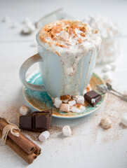Cappuccino in a blue cup with cinnamon, cream and marshmallows
