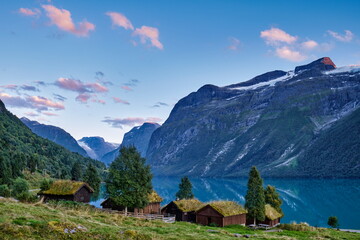 Steile Berge, See mit Hütten und Grasdach im Abendlicht, Norwegen, Skandinavien
