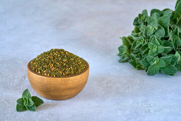 Mixed spice zaatar or zatar in wooden bowl with fresh zaatar leaves