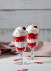 Red velvet cake in glasses with white cream on a white background. A dessert for two lovers for Valentine's Day