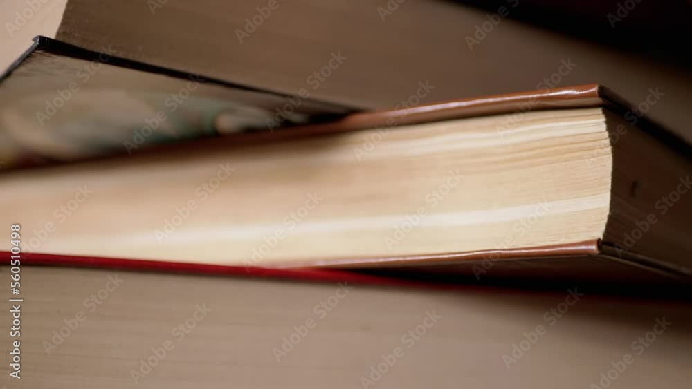 Poster close-up of a stack of colorful old hardcover books in the rays of sunlight. camera movement from bo
