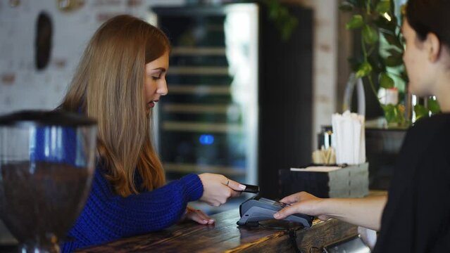 In the cafe woman pays by contactless mobile phone to credit card system, slow motion