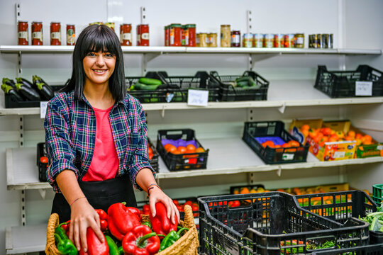 Portrait of shopkeeper in greengrocer's, sorting out red peppers